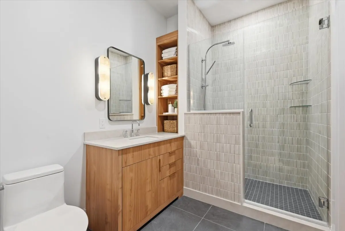 Bathroom in Model Unit 209 with walnut vanity and tiled shower